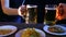 The hands of friends at the bar hit beer mugs together on a black background