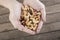 Hands full of mixed nuts over a wooden background. Peanuts, brazilian nuts, cashew nuts, baru nuts and almonds