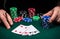 Hands of a gambler closeup and chips on green table in a poker club. A player places a bet on winning poker four of a kind or