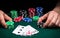 Hands of a gambler closeup and chips on green table in a poker club. A player places a bet on winning poker full house or full