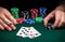 Hands of a gambler closeup and chips on green table in a poker club. A player places a bet on winning poker  three of a kind or