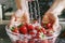 Hands gently rinsing ripe strawberries in a water-filled bowl