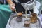 Hands of girl cooking boiling delicious turkish aromatic coffee with foam in copper turk on hot sand. Coffee preparation