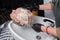 Hands of a girl in the gloves of a professional barber in the process of washing, the hair of an adult woman at work in a