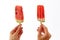 Hands of a girl holding two, appetizing, fresh slices of watermelon on a stick on a white background. The concept of