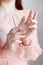 Hands of a girl in a pink lace dress with frills on a white background raised up