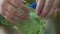 Hands of a girl playing with green kinetic sand indoors with a starfish mold