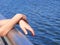 Hands of girl stands on deck of ship, hands on rail of bank of river or see, view with copyspace