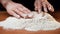 Hands of girl on wooden table unroll pile of white flour and make in middle