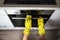 The hands of a girl in yellow gloves with a sponge wash a modern electric oven. Concept for cleaning grease stains