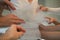 Hands of girlfriends helping the bride to dress her dress