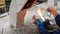 The hands of a glassblower woman holding a glass rod over the flame of a burner against the background of the workplace