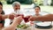 Hands, glasses and drink cheers for celebration in garden for family birthday or vacation eating, holiday or party