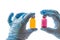 Hands in glove hold multi-colored vials on white background