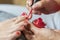 Hands in gloves cares about a woman`s foot nails. Pedicure, manicure beauty salon concept. Nail varnishing in red color.