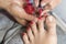 Hands in gloves cares about a woman\'s foot nails. Pedicure, manicure beauty salon concept. Nail varnishing in red color.