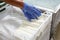 Hands in gloves packing fresh chilled mozzarella heads in a storage boxes on a cheese manufacturing plant