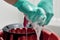 Hands with gloves wring out cleaning cloth over bucket with soap water