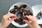 Hands Grabbing Mussel`s Meat Out by Using an Empty Mussel Shell, with a Blurry Belgian Steamed Mussels Dish in Backdrop