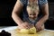 Hands of a grandmother and a child hold a dough together