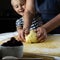 Hands of a grandmother and a child hold a dough together