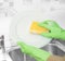 Hands in green gloves wash white plate