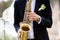 Hands of groom play on saxophone