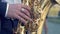 Hands of groom play on saxophone. Closeup hands of man playing golden alto saxophone with light effect. Men playing