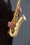 Hands of groom play on saxophone on grey background