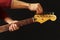 Hands of guitarist tunes the electric guitar on black background