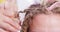 Hands of hairdresser undo colored braids client, unraveling curly locks of hair