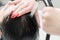 Hands of hairstylist wash hair of brunette with shampoo in professional sink for shampooing in beauty salon