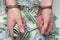 Hands in handcuffs hold money