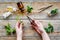 Hands harvest medicinal herb. Leaves, bottles and sciccors on wooden background top view