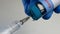Hands of healthcare worker in protective gloves draw Covid-19 coronavirus vaccine into new disposable syringe from glass