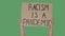 Hands hold a poster with the slogan RACISM IS A PANDEMIC against the background of a green screen, chroma key. Stop