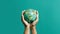 Hands hold a small globe on a green background created with Generative AI. Save the planet.