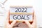 Hands holding 2022 goals wood box over marble background, banner, business new year, aim to success in business