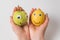 Hands holding Apple and lemon with funny faces on white background