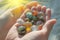 hands holding assorted marbles against a bright backdrop
