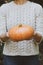 Hands holding beautiful freshly picked organic orange pumpkin.