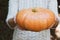 Hands holding beautiful freshly picked organic orange pumpkin.