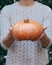 Hands holding beautiful freshly picked organic orange pumpkin.