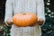 Hands holding beautiful freshly picked organic orange pumpkin.