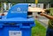 _Hands holding brown flattened cardboard box putting it into a blue recycling bin. Selective focus