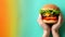 Hands holding burger on soft colored backdrop with ample space for text placement