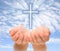 Hands holding Christian cross with light beams