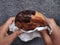 Hands holding Cromboloni, Round Croissant, New York Roll, a viral pastry combining croissants and bomboloni on concrete wall