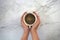 Hands holding a cup of coffee, with marble background