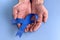 Hands holding deep blue ribbon on blue background with copy space. Colorectal Cancer Awareness. Colon cancer of older person.